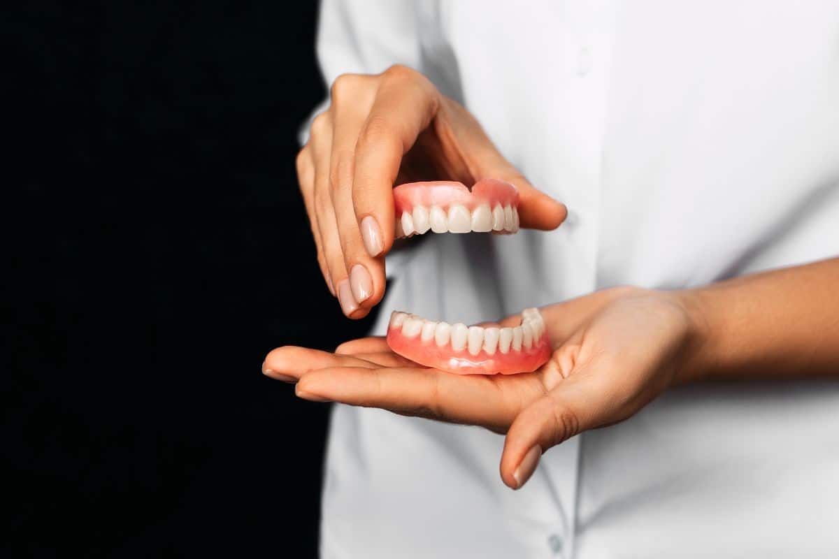 man holding dentures set for both upper and low jaw