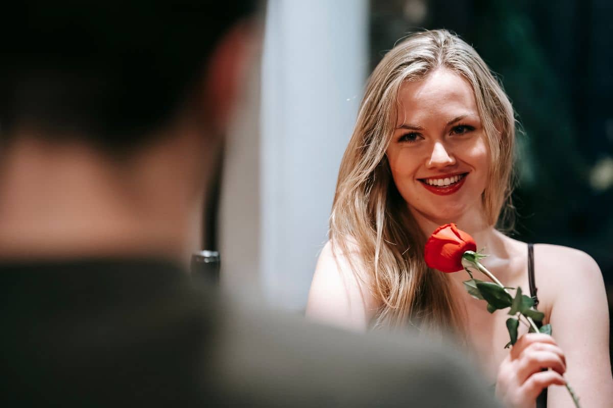 woman smiling holding a rose