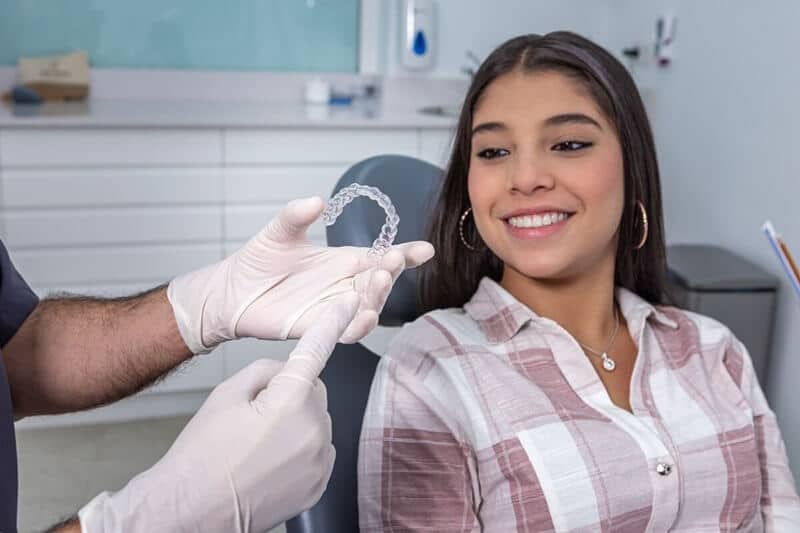 dentist showing woman how Invisalign can work even after crown or implant